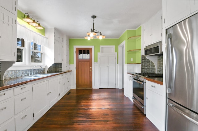 kitchen featuring white cabinets, a sink, dark wood finished floors, stainless steel appliances, and decorative backsplash