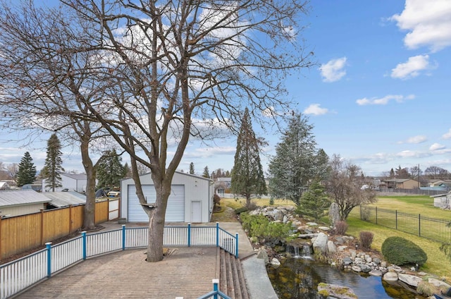 exterior space featuring an outbuilding, a detached garage, decorative driveway, a lawn, and fence