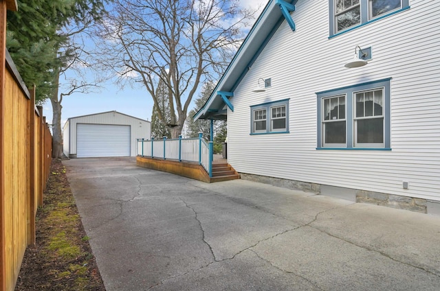 view of property exterior featuring driveway, a garage, fence, and an outdoor structure