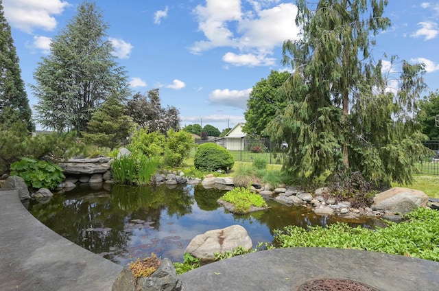 view of water feature with a garden pond and fence