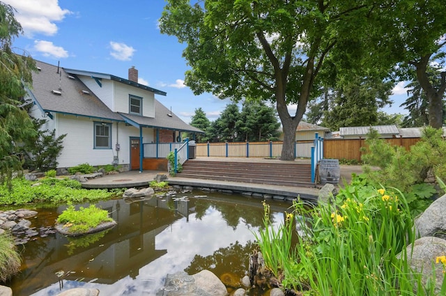 dock area featuring fence, a small pond, and a deck