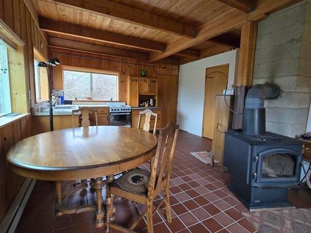 3434G Rockcut Rd, Kettle Falls, WA 99141 - dining area with wood ceiling with exposed beams, a wood stove, wood walls, and dark tile patterned floors