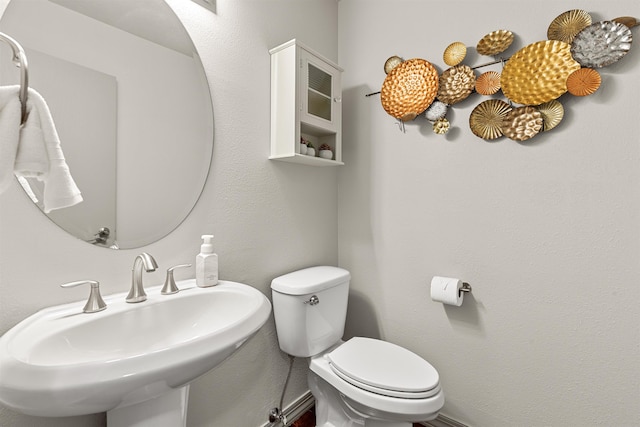 half bath with a sink, toilet, and baseboards