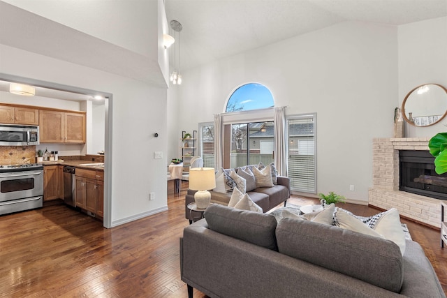 living area with high vaulted ceiling, dark wood-style floors, a fireplace, and baseboards