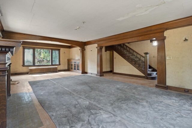 540 E Rockwood Blvd, Spokane, WA 99202 - unfurnished living room with decorative columns, arched walkways, radiator heating unit, stairway, and baseboards