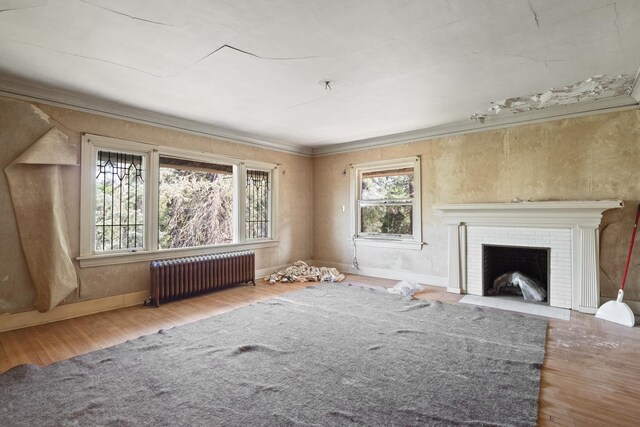 540 E Rockwood Blvd, Spokane, WA 99202 - unfurnished living room featuring radiator, ornamental molding, wood finished floors, a brick fireplace, and baseboards