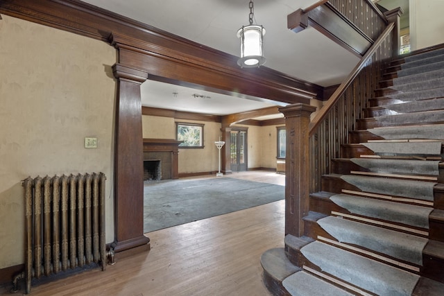 540 E Rockwood Blvd, Spokane, WA 99202 - stairs with decorative columns, arched walkways, radiator heating unit, a large fireplace, and wood finished floors