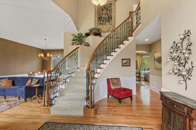 4357 S Greystone Ln, Spokane, WA 99203 - stairs with an inviting chandelier, arched walkways, a towering ceiling, a wainscoted wall, and wood finished floors