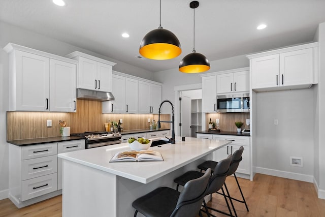 13310 N Starling Ln, Spokane, WA 99208 - kitchen featuring a sink, appliances with stainless steel finishes, dark countertops, under cabinet range hood, and white cabinetry