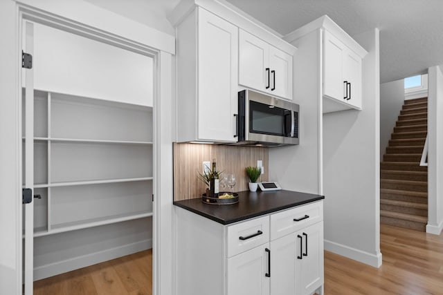 13310 N Starling Ln, Spokane, WA 99208 - kitchen with stainless steel microwave, baseboards, dark countertops, white cabinets, and light wood finished floors