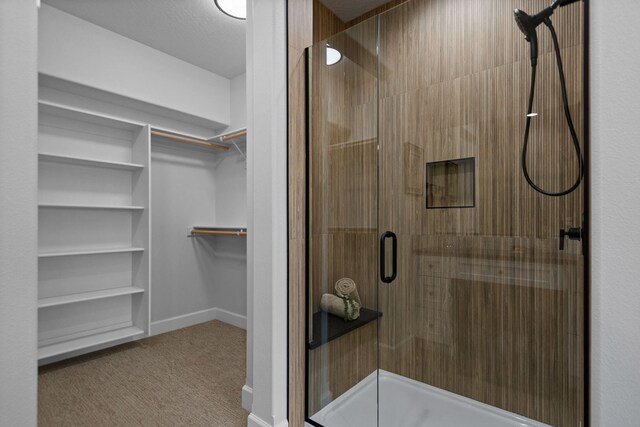 13310 N Starling Ln, Spokane, WA 99208 - bathroom featuring baseboards, a walk in closet, and a stall shower