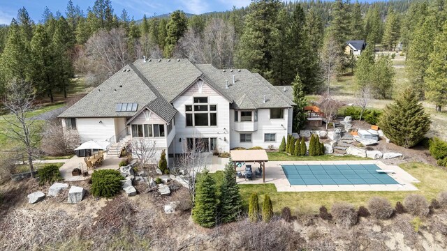 13615 N Riverbluff Ln, Spokane, WA 99208 - rear view of property with a patio, a covered pool, stairs, outdoor dining area, and a forest view