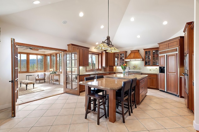 13615 N Riverbluff Ln, Spokane, WA 99208 - kitchen featuring custom exhaust hood, built in appliances, vaulted ceiling, and light tile patterned flooring