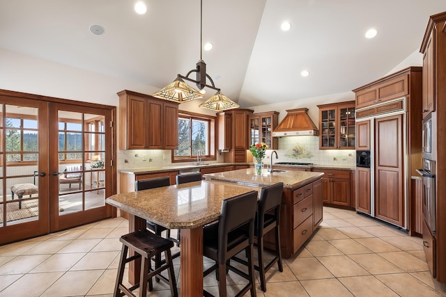 13615 N Riverbluff Ln, Spokane, WA 99208 - kitchen with premium range hood, built in appliances, light tile patterned floors, and a center island with sink