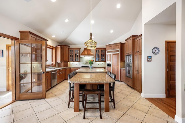13615 N Riverbluff Ln, Spokane, WA 99208 - kitchen with stainless steel appliances, light tile patterned floors, a center island, and brown cabinetry
