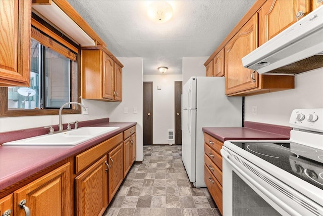 2121 E Upriver Dr Unit # 61, Spokane, WA 99207 - kitchen with white electric stove, under cabinet range hood, stone finish floor, brown cabinets, and a sink