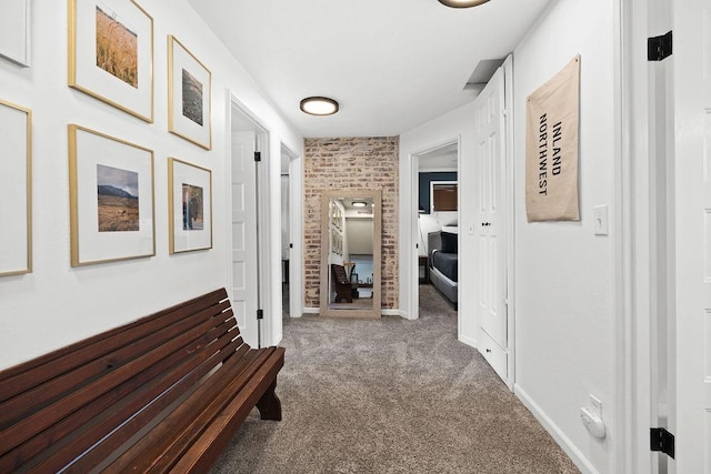 hallway featuring brick wall, baseboards, and carpet floors