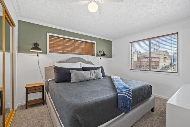 bedroom featuring a ceiling fan, light colored carpet, a textured ceiling, and ornamental molding