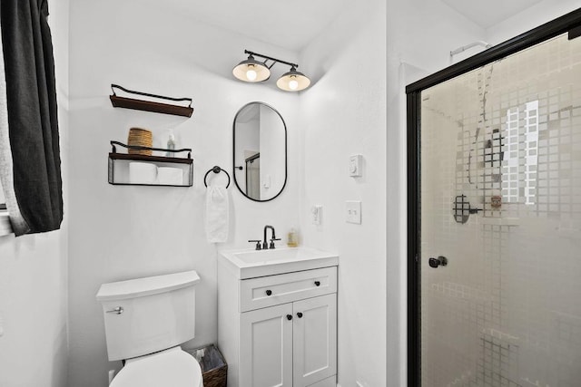 bathroom with toilet, a stall shower, and vanity