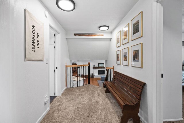 corridor with carpet, baseboards, lofted ceiling, and an upstairs landing