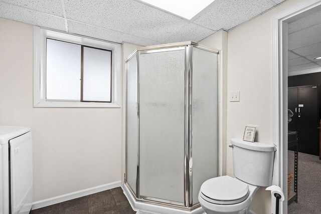 full bath featuring washer / clothes dryer, baseboards, toilet, a drop ceiling, and a stall shower