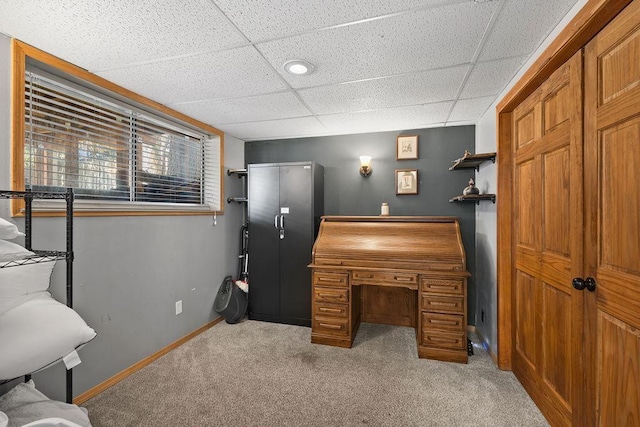 office space with light carpet, a paneled ceiling, and baseboards