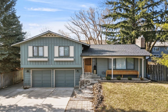 tri-level home featuring an attached garage, fence, driveway, and a chimney