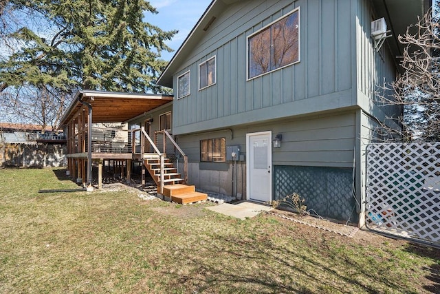 back of property with stairway, board and batten siding, and a lawn