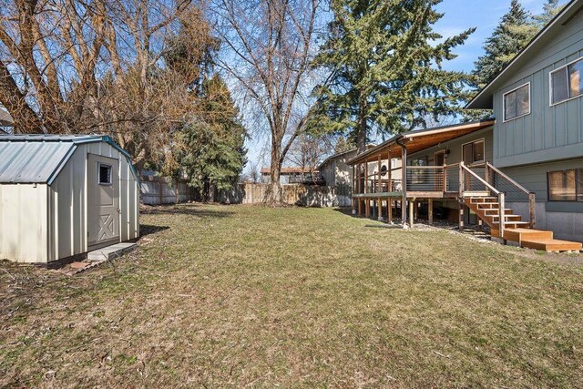 view of yard with a storage shed, a fenced backyard, stairway, an outbuilding, and a wooden deck
