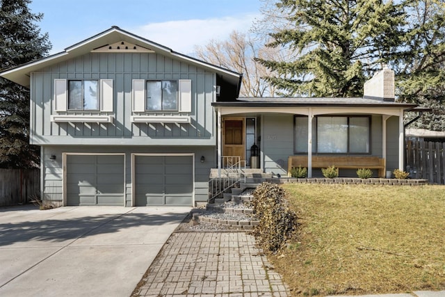tri-level home featuring board and batten siding, a front yard, fence, an attached garage, and concrete driveway