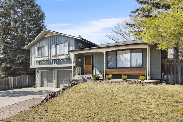 tri-level home with a porch, fence, a front lawn, an attached garage, and concrete driveway