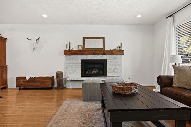 living area featuring a fireplace, recessed lighting, wood finished floors, and a textured ceiling