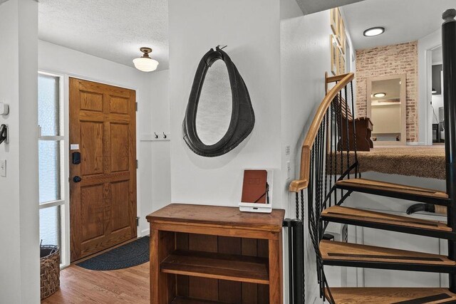 foyer with a textured ceiling, wood finished floors, and stairs