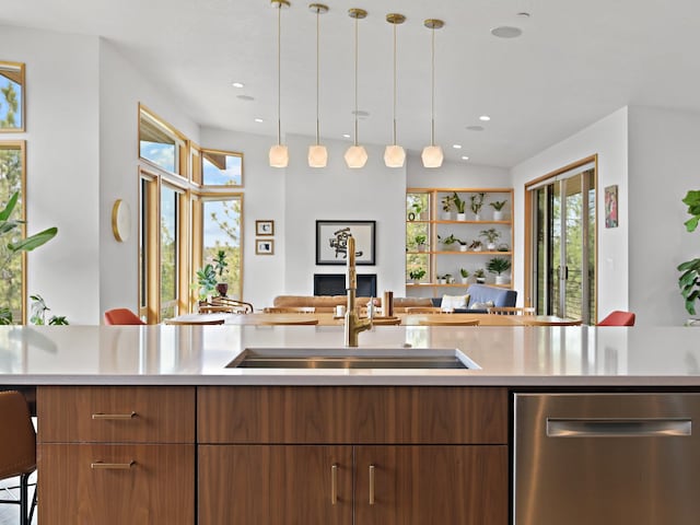 kitchen featuring plenty of natural light, a sink, open floor plan, light countertops, and stainless steel dishwasher