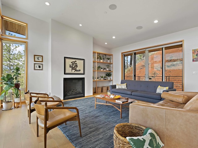 living room featuring recessed lighting, vaulted ceiling, wood finished floors, and a fireplace