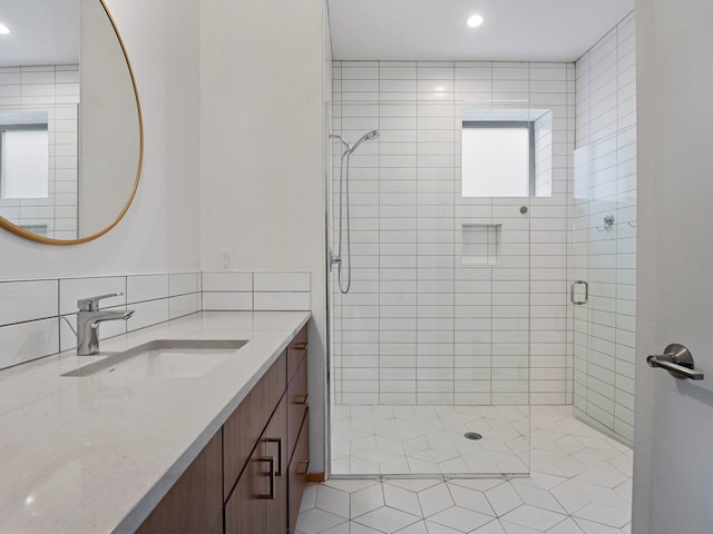 full bath with a shower stall, vanity, and decorative backsplash