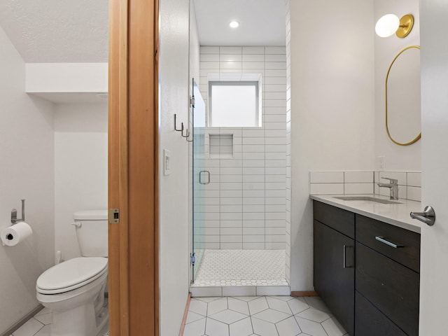 bathroom with vanity, tile patterned flooring, toilet, a stall shower, and baseboards