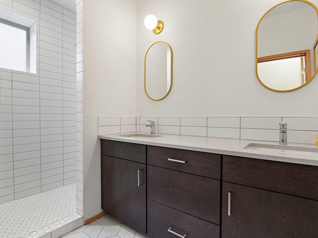 full bathroom with tile patterned flooring, double vanity, a tile shower, and a sink