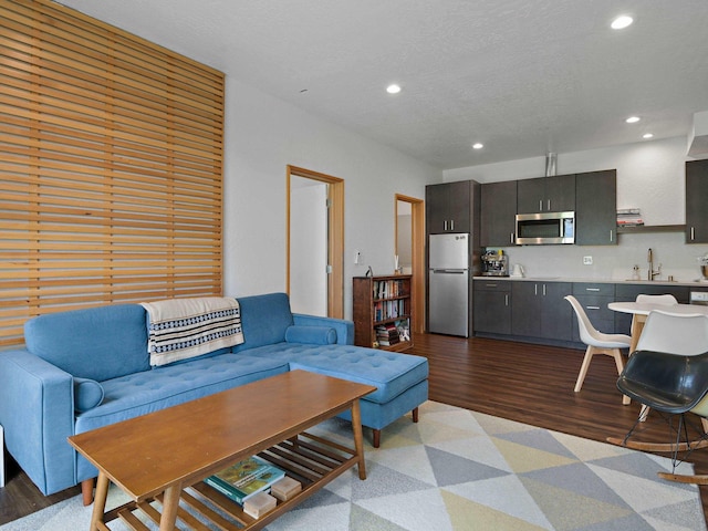 living area featuring light wood-type flooring, a textured ceiling, and recessed lighting
