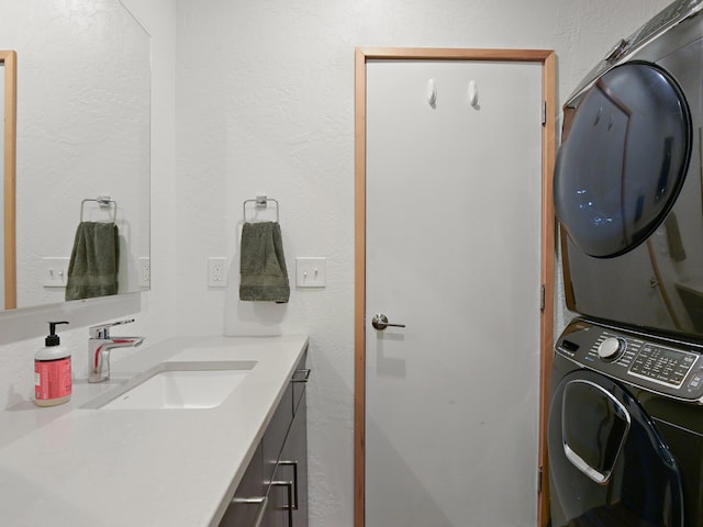 interior space with a sink, a textured wall, stacked washing maching and dryer, and laundry area