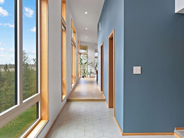 hallway featuring a healthy amount of sunlight, light tile patterned floors, baseboards, and recessed lighting
