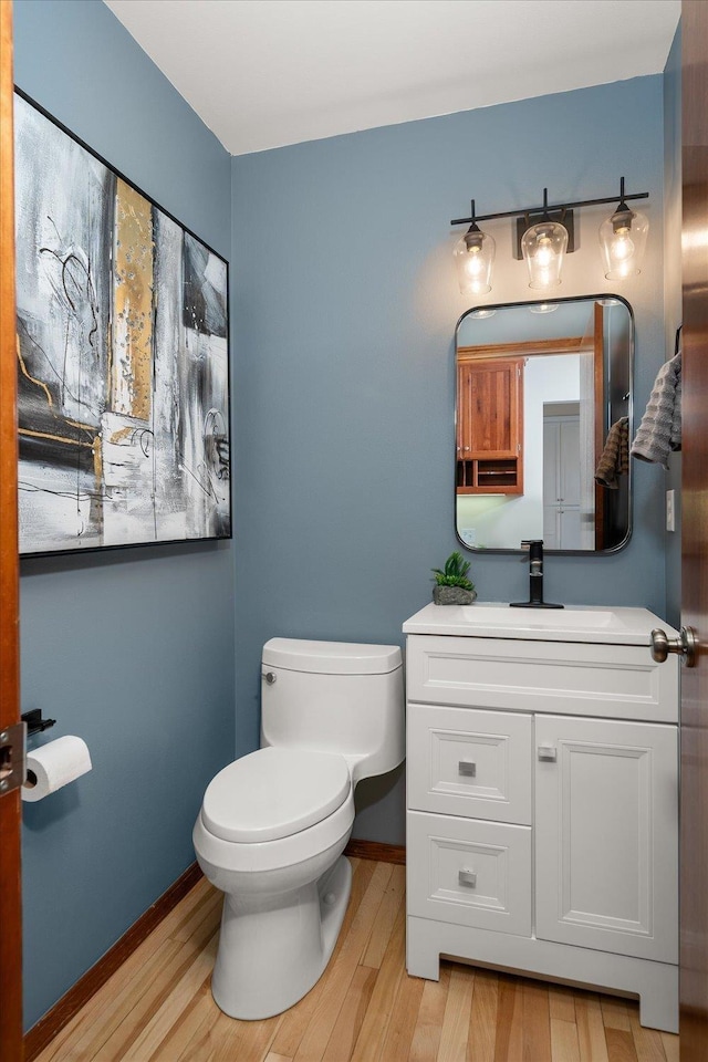 bathroom with baseboards, wood finished floors, toilet, and vanity