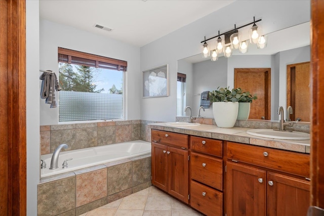 bathroom with tile patterned floors, visible vents, a bath, and a sink