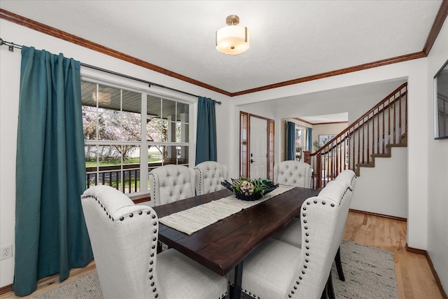 dining area featuring baseboards, stairway, ornamental molding, and light wood-style floors