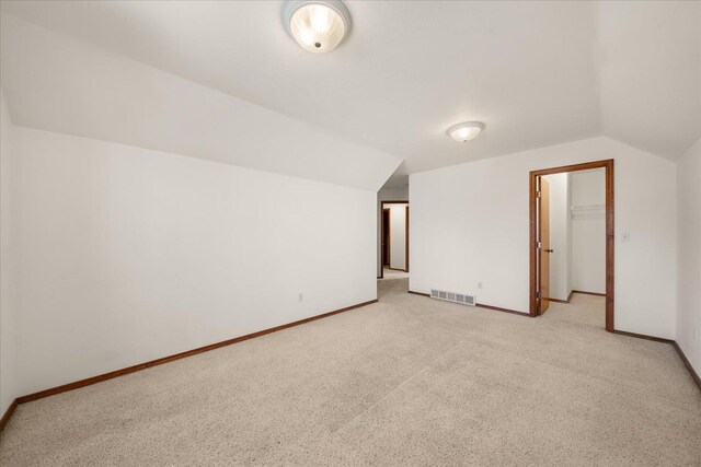 bonus room with visible vents, baseboards, vaulted ceiling, and light carpet