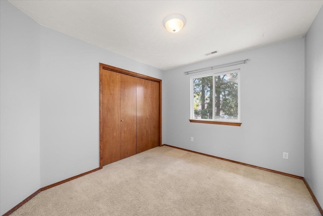 unfurnished bedroom featuring carpet, visible vents, and a closet