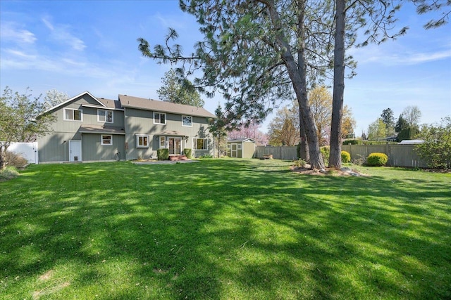 rear view of property featuring a lawn, a storage unit, an outbuilding, and a fenced backyard