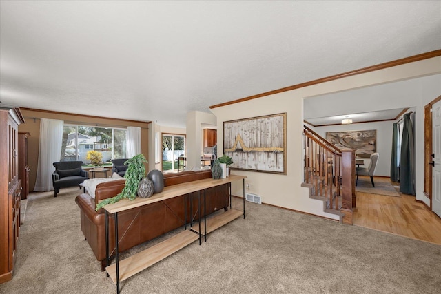 living area with ornamental molding, carpet, visible vents, and stairway