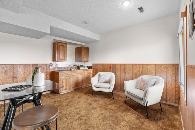living area featuring wood walls, wainscoting, and light carpet