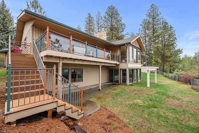 rear view of house with a deck, a lawn, a chimney, fence, and stairway